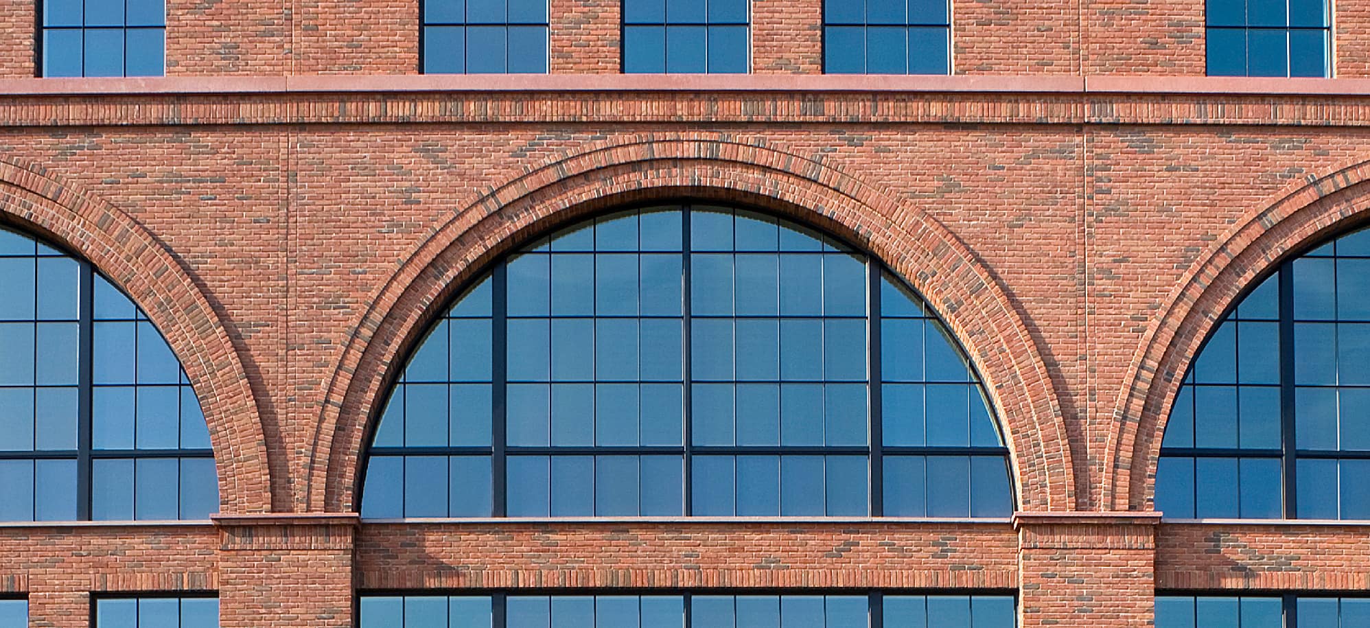 Arched red brick facade cast with Advanced embedded thin brick, brick against blue glass